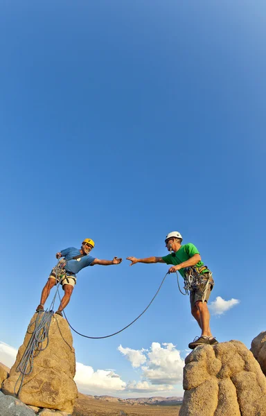 Rock climbing team reaching the summit.