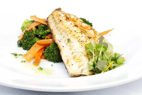 Fresh black cod on bed of broccoli and carrots