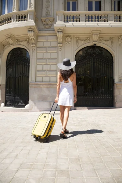 Woman back walking with suitcase