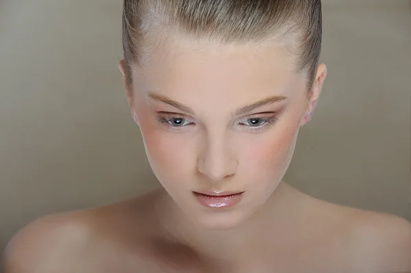 Beautiful young girl with health skin of face and delicate makeup look down