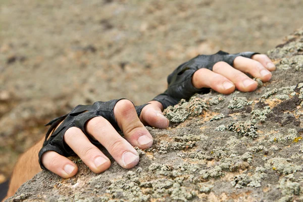 Two hands of rock-climber hanging on stone