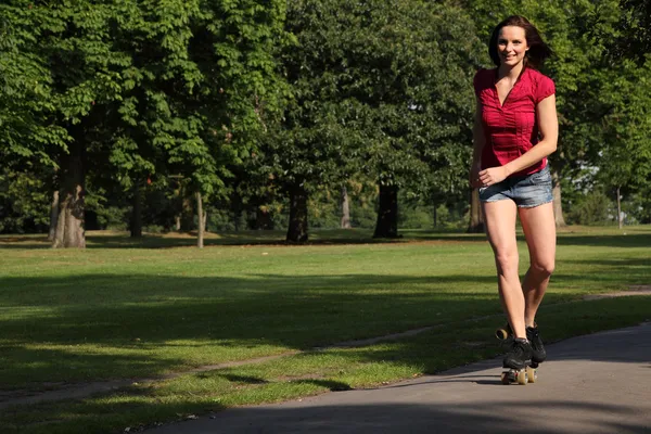 Sexy young woman roller skating in park sunshine