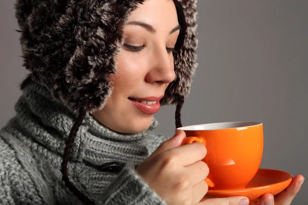 Young woman in warm winter hat drinking hot tea
