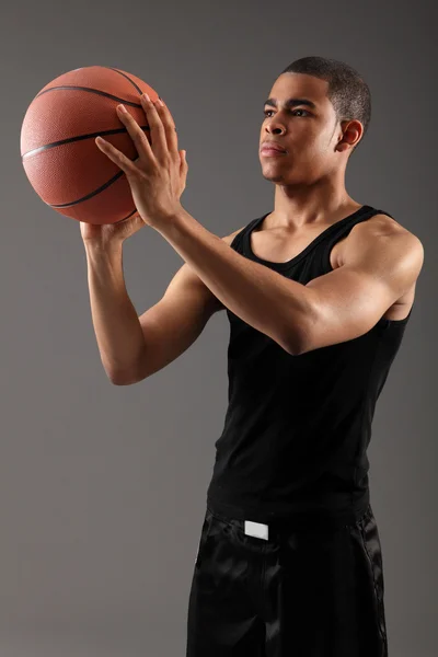Young black man shooting hoops with basketball
