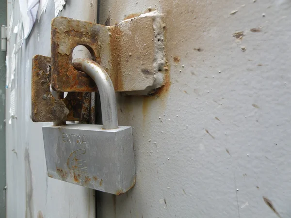 Shiny lock locks rusty gate