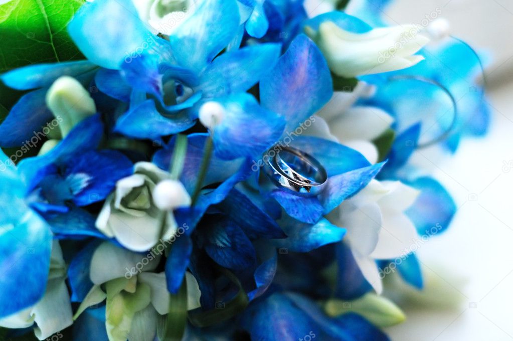 Two wedding rings on a wedding azure flowers bouquet