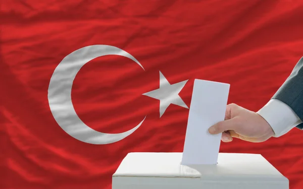 Man voting on elections in turkey in front of flag