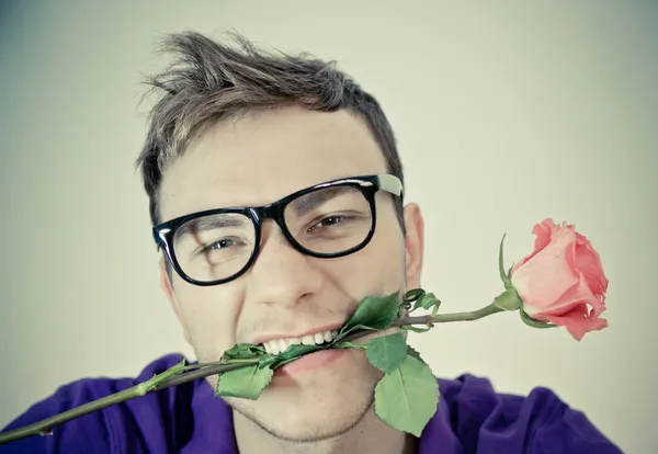 Young man holding rose in his mouth