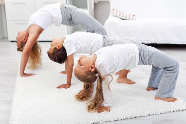 Woman and kids doing gymnastic exercises at home