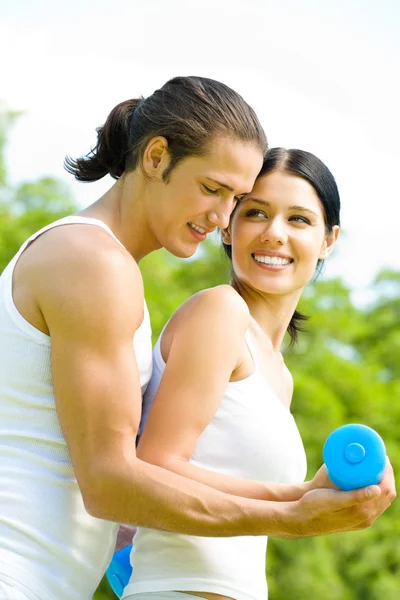 Young happy smiling couple in sport wear doing fitness exercise