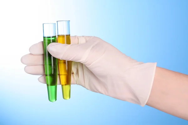 Test tubes with fluid in hand on blue background