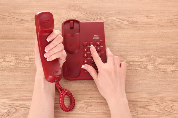 Red phone and hands on wooden table
