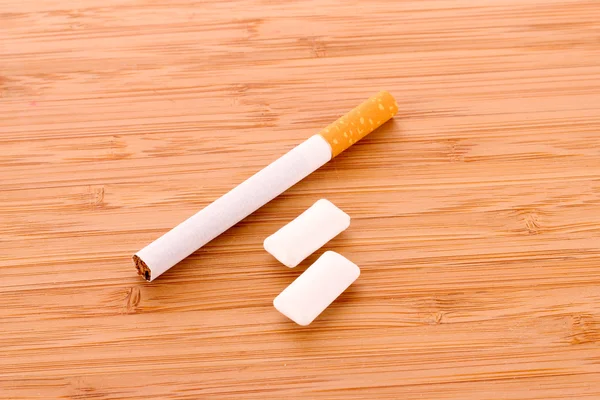 Cigarette and chewing gum on wooden table