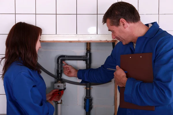 A mature plumber teaching to a female apprentice