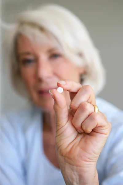 Older woman holding a pill