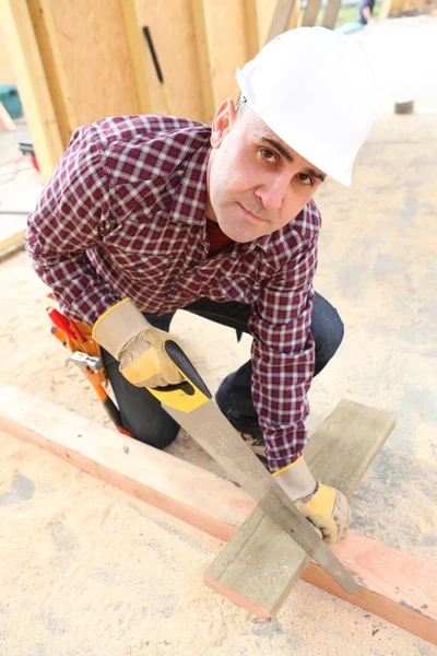 Builder sawing wood