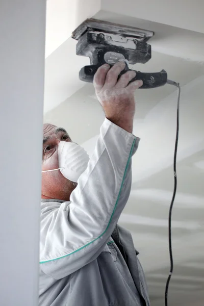 Decorator sanding a plaster ceiling