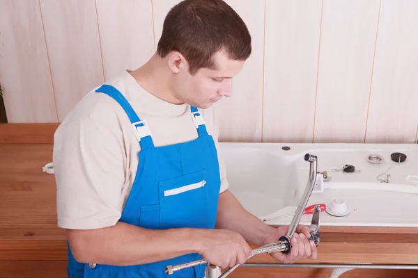 Plumber fitting a tap on a kitchen sink