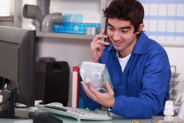 DIY store employee holding part and speaking on telephone