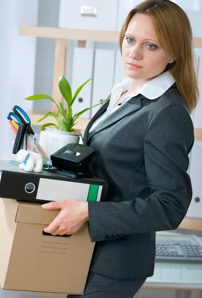 Woman laid off from her white collar job carries a box of her belongings