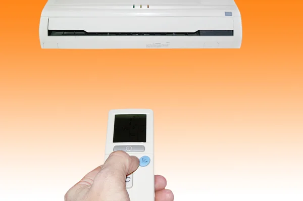 Hand with remote control directed on the air conditioner