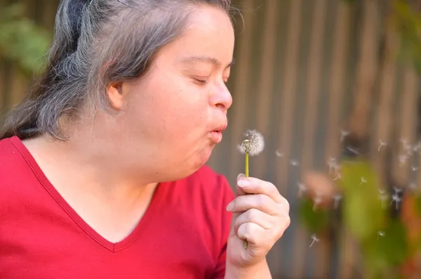 Down syndrome woman blowing dandelion