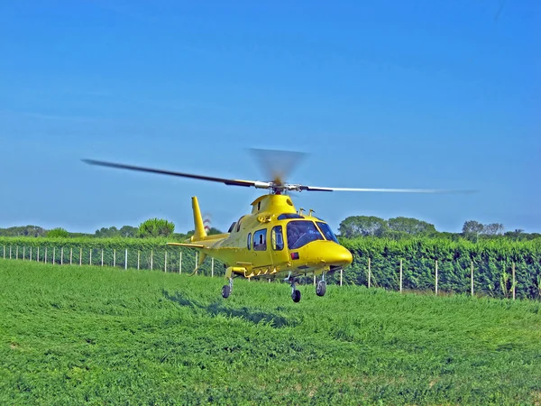 Yellow helicopter ambulance takes off with an injured person on board and f