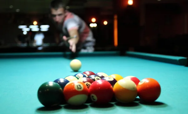 close up of pool table and balls pictured mid game under billiard hall ligh
