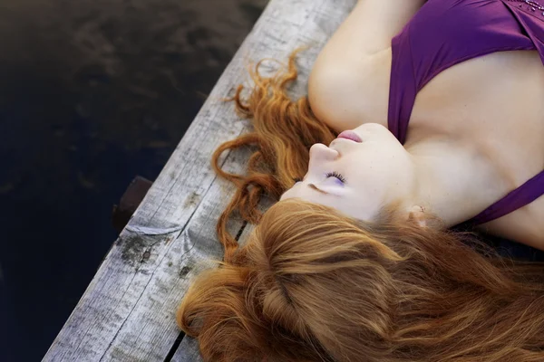 Beautiful red-haired girl on the pier in a purple dress — Stock Photo #7533122