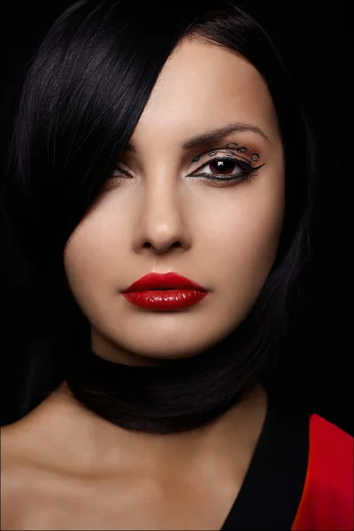 Beautiful young woman with red lips and long black hair isolated on black by