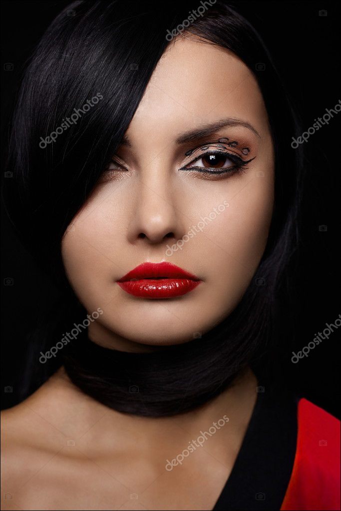 Beautiful young woman with red lips and long black hair isolated on black