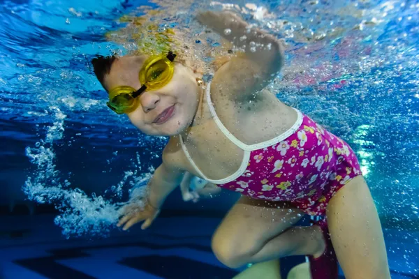 Happy cute girl toddler swimming underwater