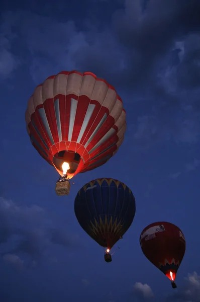 Three hot air balloons flying by night
