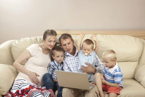 Family sitting on the sofa and watching laptop