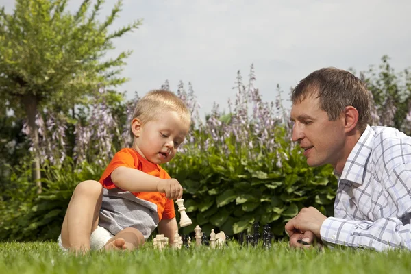 Child and father playing chess in the garden
