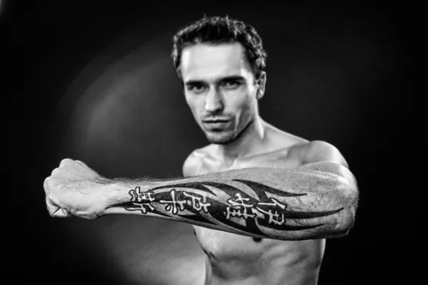 Man showing hand with tattoo made in studio on dark background focus on arm