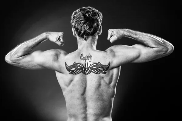 Man showing tattoo on his back made in studio on dark background - Stock  Image - Everypixel