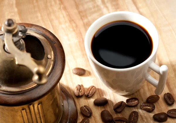 Кофе натюрморт с чашкой и мельница над деревянным столом — стоковое фото