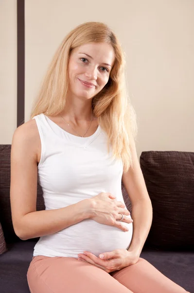 Femme enceinte souriante sur le canapé — Photo