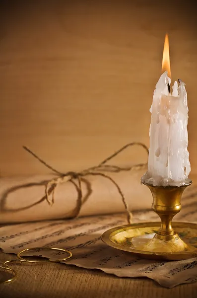 Античная свеча на столе с музыкальными нотами — стоковое фото