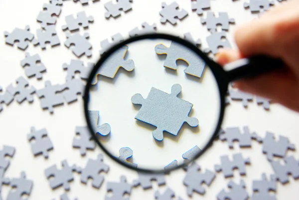 Magnifying glass and puzzle — Stock Photo, Image