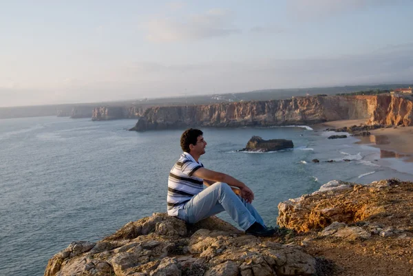 Людина сидить на скелі в Sagres — стокове фото