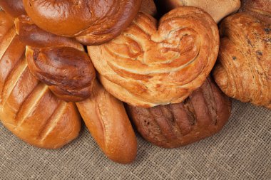 Variety of fresh bread over sacking background clipart