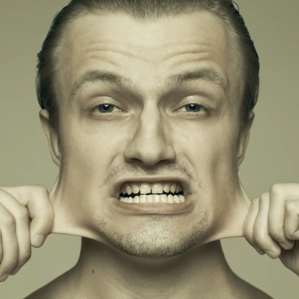 Retrato do jovem homem esticando suas bochechas — Fotografia de Stock