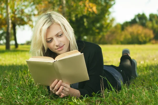 Menina bonita lendo no parque na grama — Fotografia de Stock