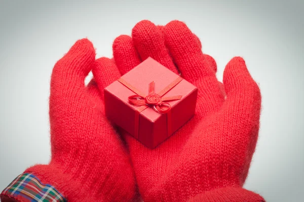 Mani dando scatola rossa con presente su sfondo grigio — Foto Stock