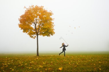 Happy young girl catching autumn leafes with net clipart