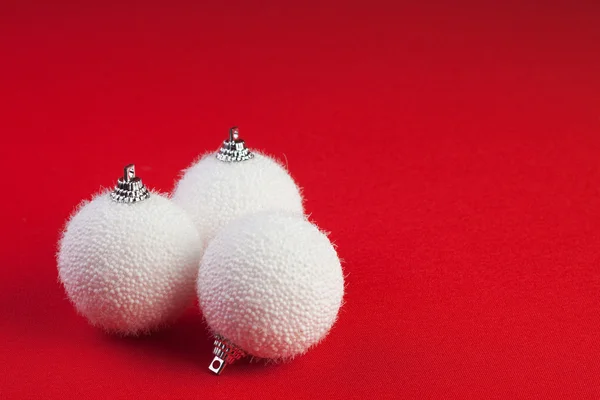 Three white christmas balls over red background — Zdjęcie stockowe