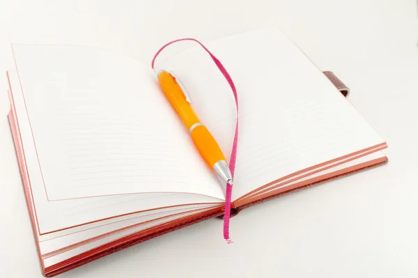 Ноутбук и оранжевая ручка — стоковое фото