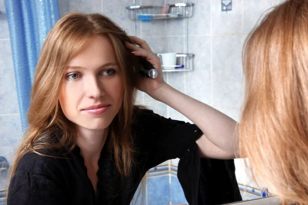 Banyoda saç düzeltme bir ayna önünde genç kadın — Stok fotoğraf